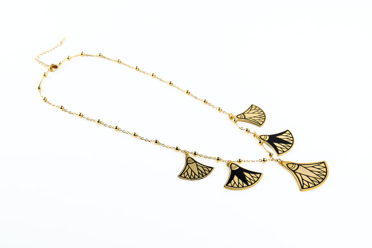 A gold chain necklace featuring five ancient Egyptian lotus  pendant charms with black and gold patterns, displayed on a clean white background.