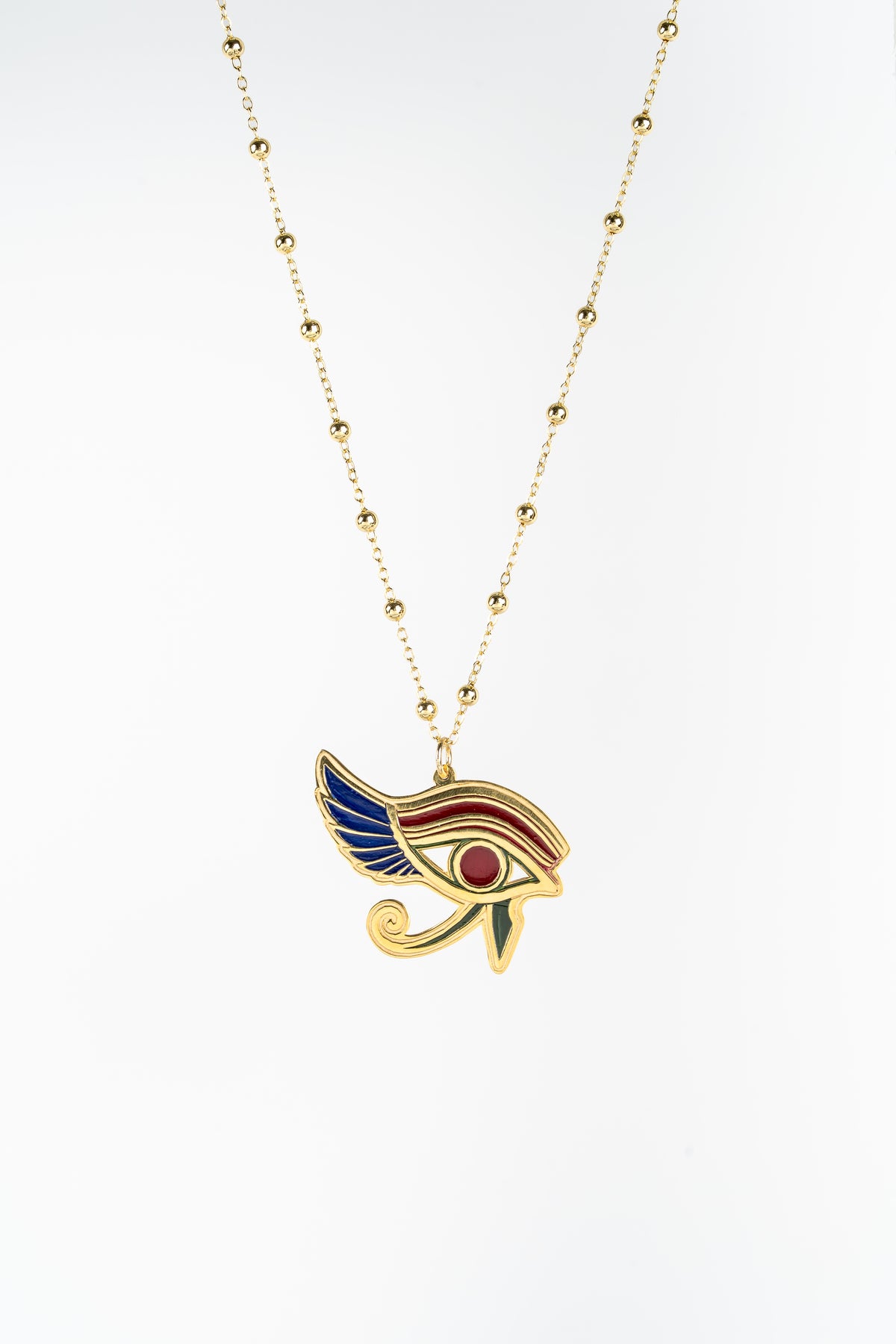A gold-plated necklace featuring an Egyptian Eye of Horus pendant with blue, red, and gold enamel details, shown against a plain white background.