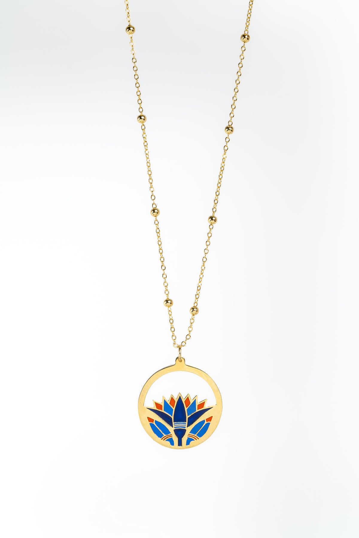 A gold necklace with a circular pendant featuring a stylized lotus flower in blue, red, and gold, suspended against a clean white background.