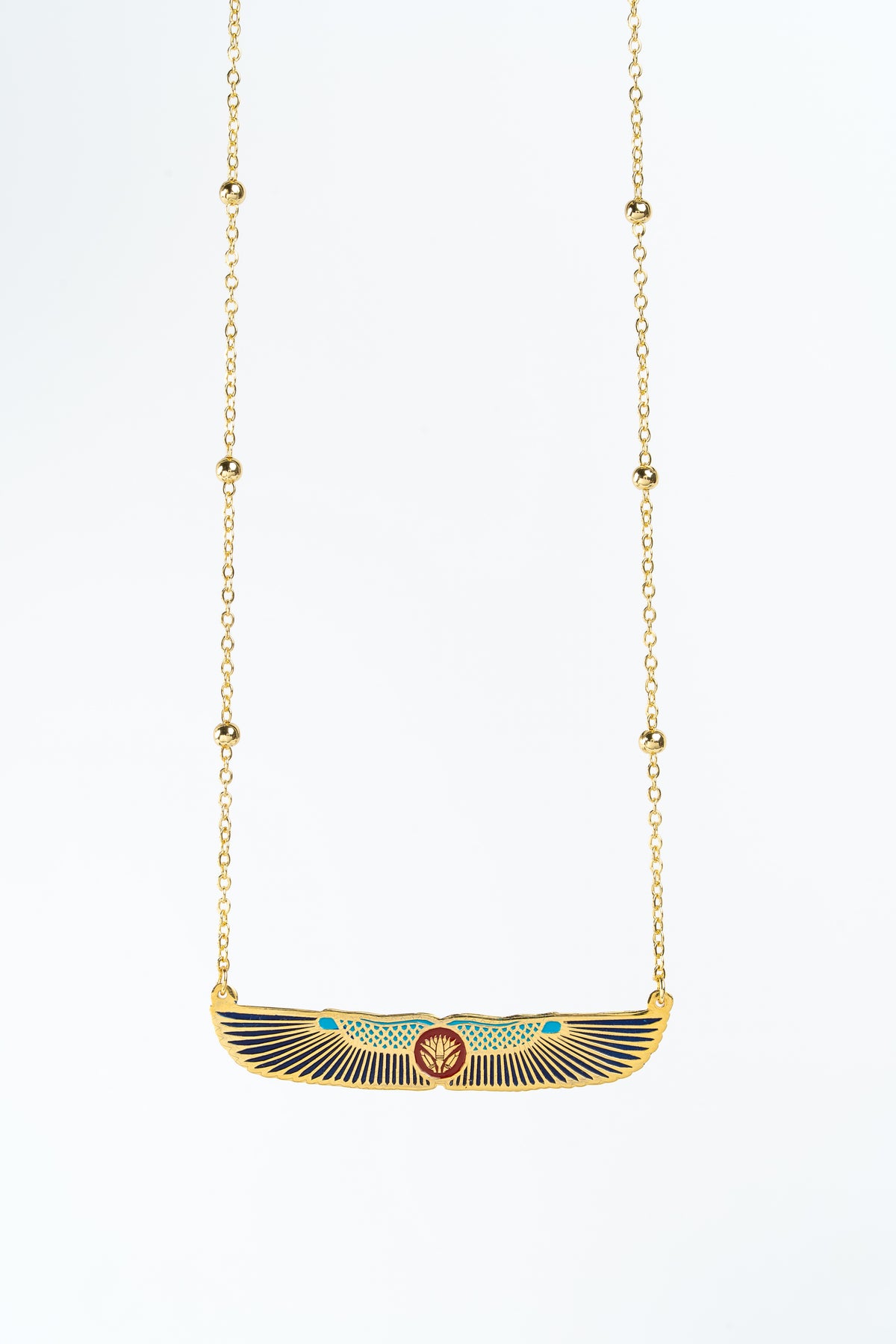 A gold-plated pendant necklace featuring an Egyptian winged lotus in sun motif with navy, blue, and red enamel details, suspended on a delicate gold-toned chain against a plain white background.