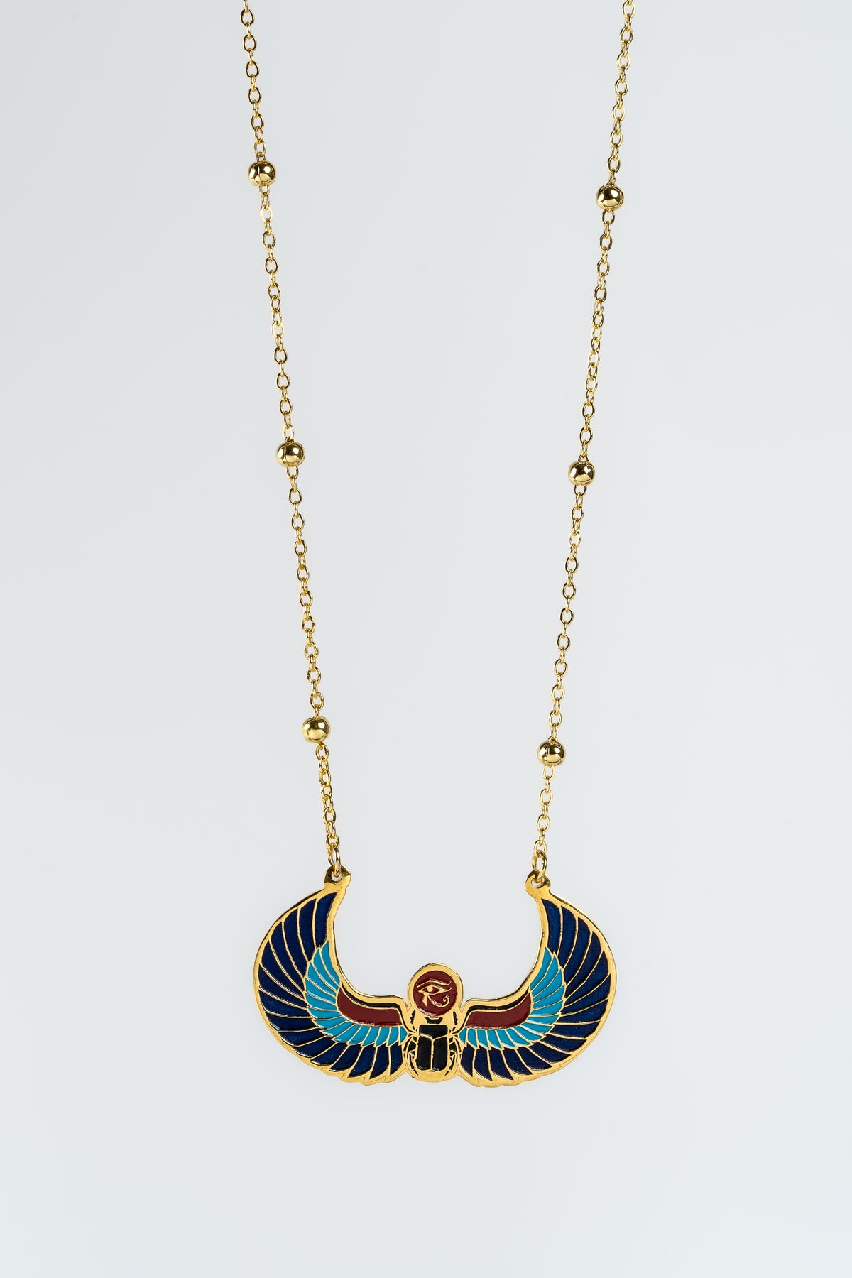A statement piece that is an Ancient-Egyptian-themed winged scarab pendant necklace on a gold chain, displayed on a white background
